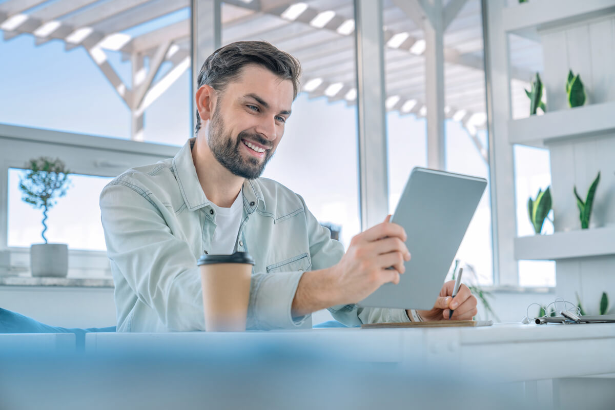 smiling man working on his digital tablet at a cof 2026 03 17 04 01 59 utc